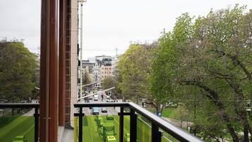 Une vue depuis un balcon donnant sur une rue, avec des voitures et une piste cyclable verte.