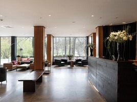 Un vestíbulo amplio con mostrador de recepción, zona de estar y ventanas grandes que ofrecen vistas al exterior.