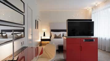 Ein Hotelzimmer mit einem Bett, einem Fernseher auf einem roten Schrank, einem Sessel, einem Schreibtisch und einer Lampe.
