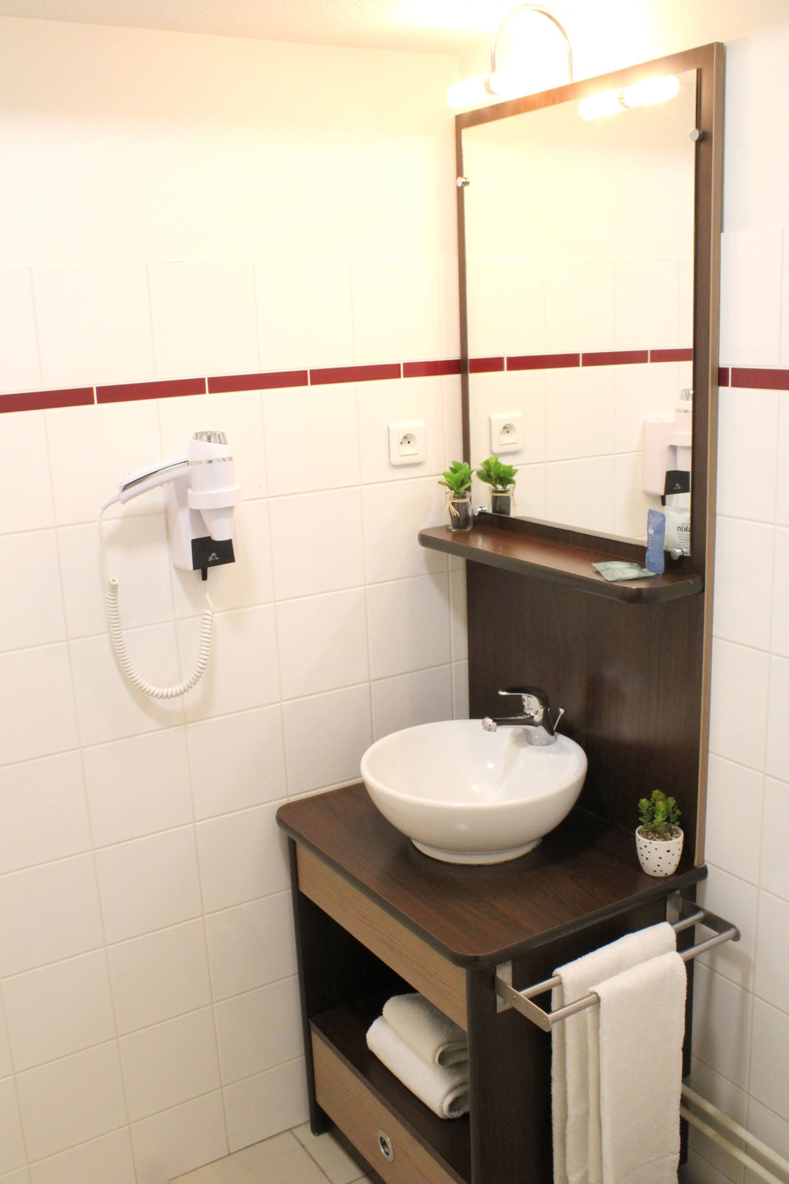 A bathroom with a white sink, a mirror, a towel rack, and a hairdryer.