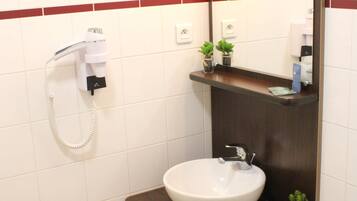 A bathroom with a white sink, a mirror, a towel rack, and a hairdryer.