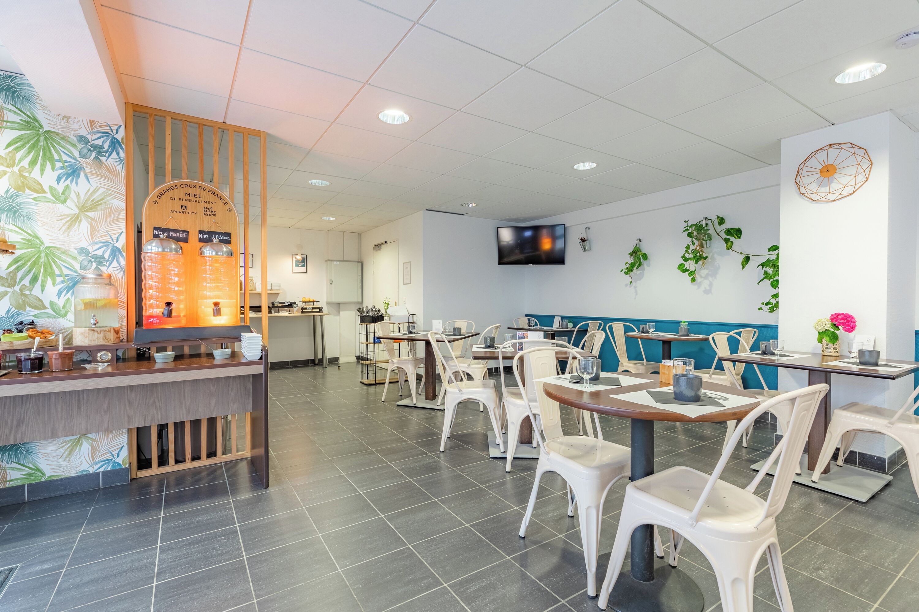 A restaurant with a counter, seating area, and a TV mounted on the wall.
