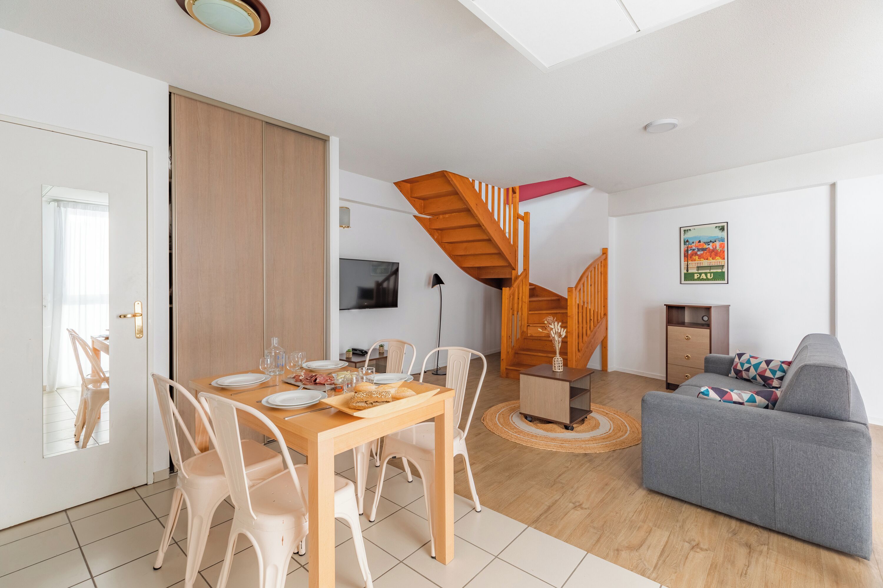 Un salon moderne comprenant un coin repas, un canapé, un escalier et un téléviseur.