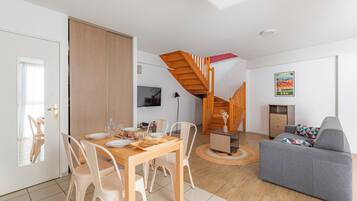 Un salon moderne comprenant un coin repas, un canapé, un escalier et un téléviseur.