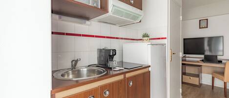 A compact kitchen with a microwave, coffee maker, and a refrigerator.