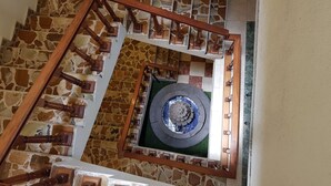 Escadaria em espiral com parede de pedra e plataforma circular central.