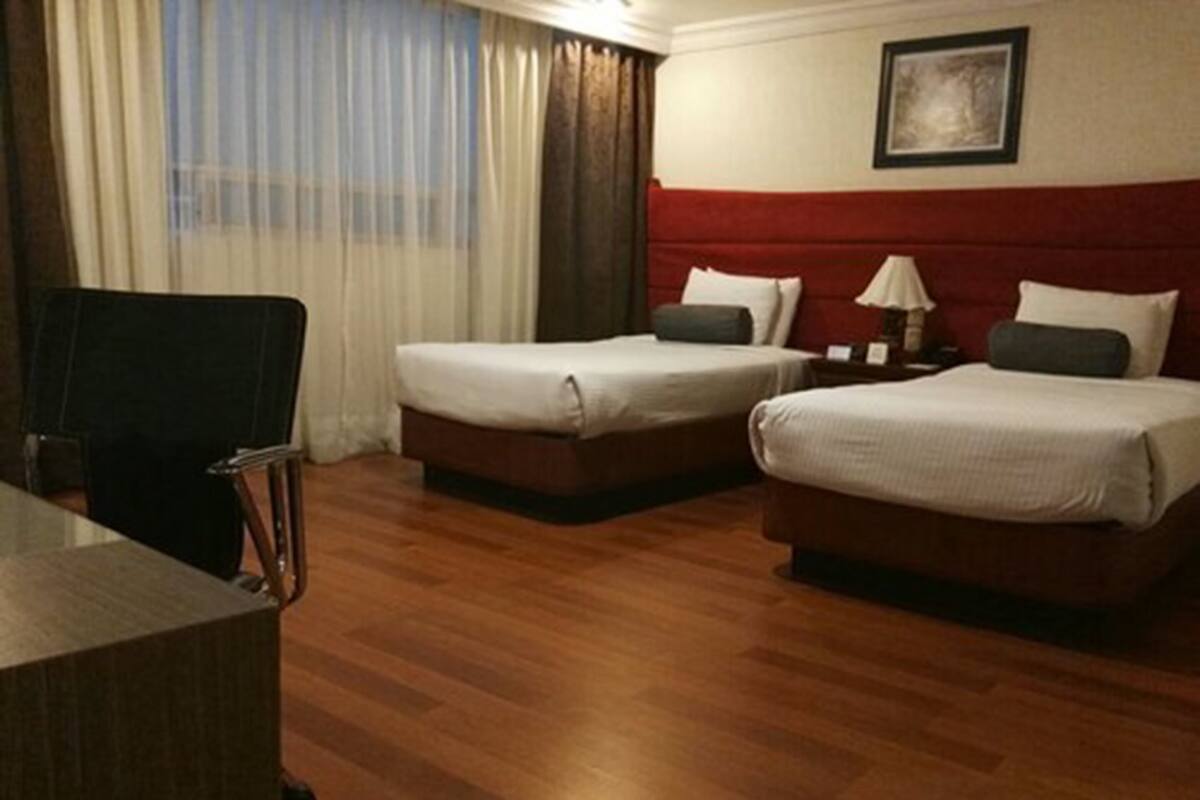 Une chambre d’hôtel avec deux lits, un bureau et une chaise.