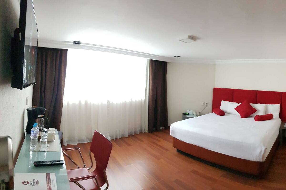 Une chambre d’hôtel comprenant un lit, un bureau avec une machine à café, une chaise et un téléviseur.