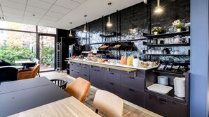 A modern kitchen with dark cabinetry, a central island, and a breakfast bar. - Brit Hotel Du Stade (Rennes)