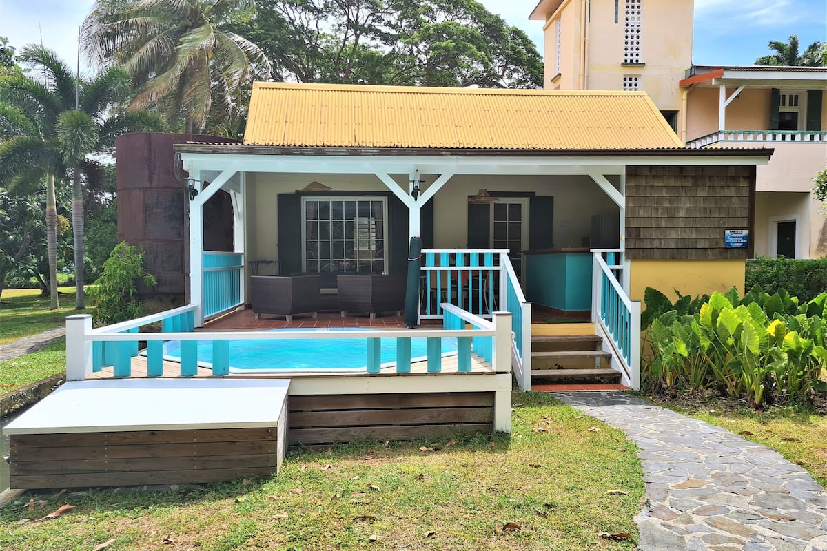 Un bâtiment à deux étages doté d’un espace extérieur couvert comprenant une piscine, une terrasse en bois et des rampes bleues.