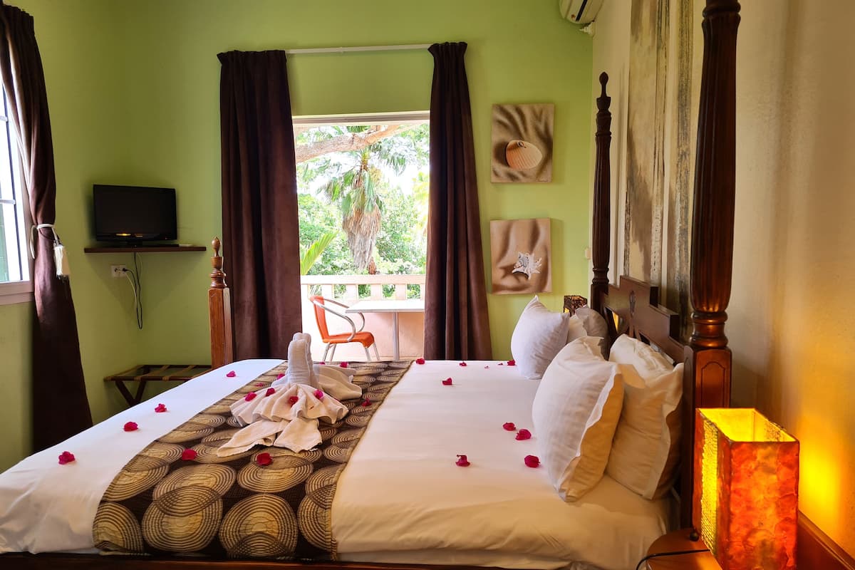 Une chambre d’hôtel avec un lit, une télévision, une fenêtre avec des rideaux, une chaise et une table.