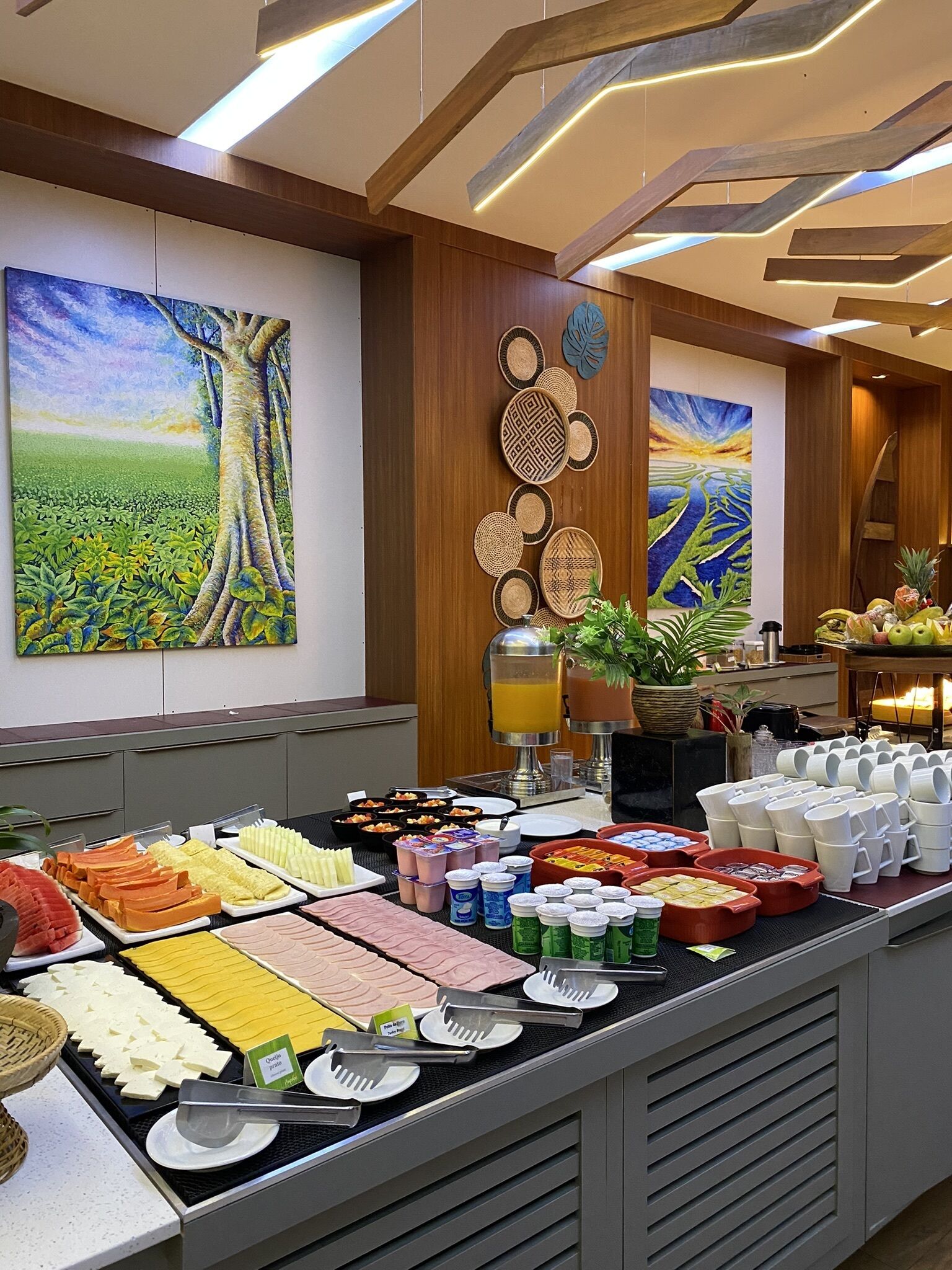 Buffet com diversos alimentos e um dispensador de sucos.