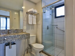 Ein Badezimmer mit Waschbecken auf einer Granitplatte, einer Toilette und einer Duschkabine.