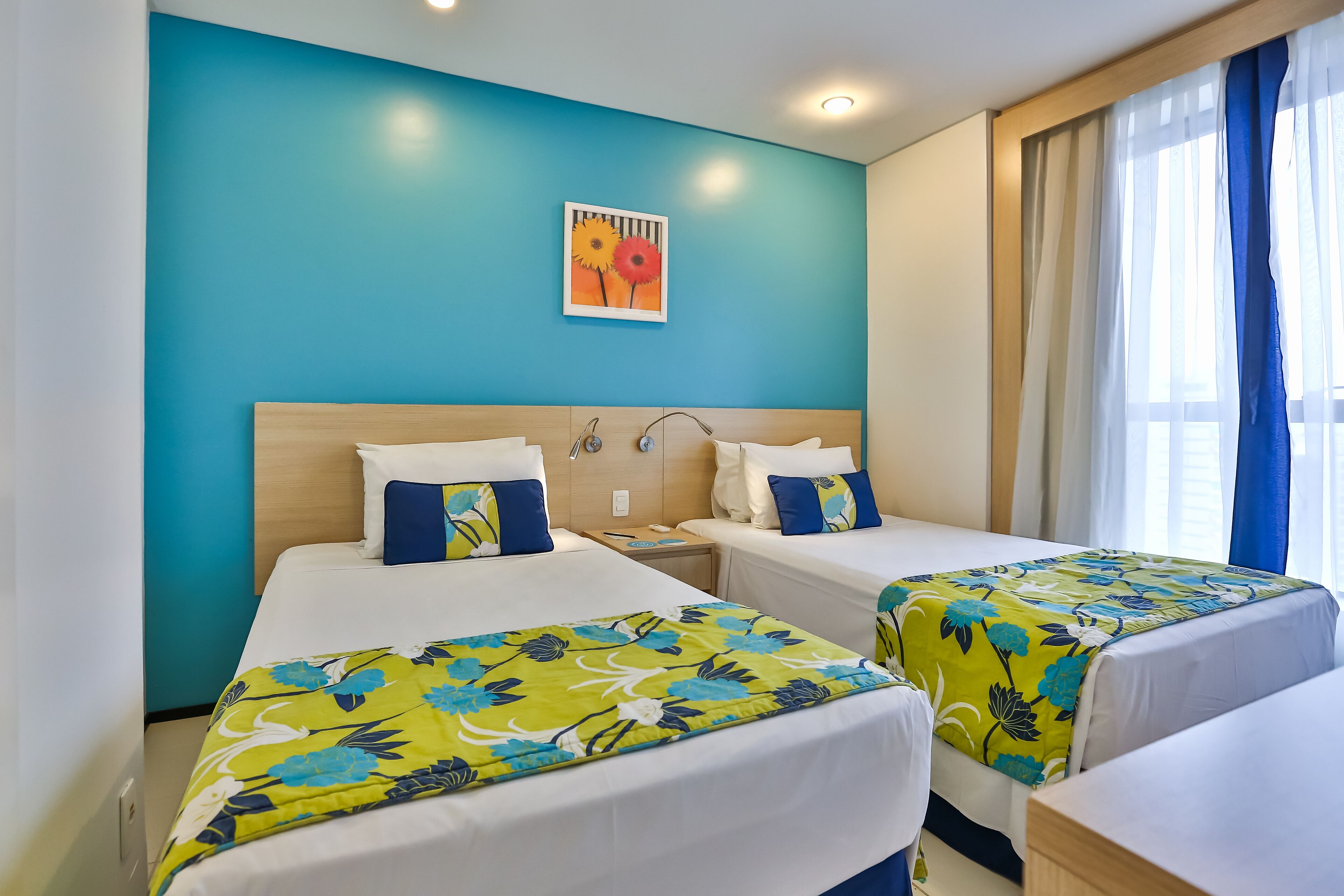 Habitación de hotel con dos camas, cabecero de madera, mesita de noche y un cuadro en la pared.