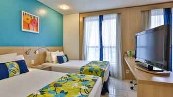 A hotel room with two beds, a TV, and a window with curtains.