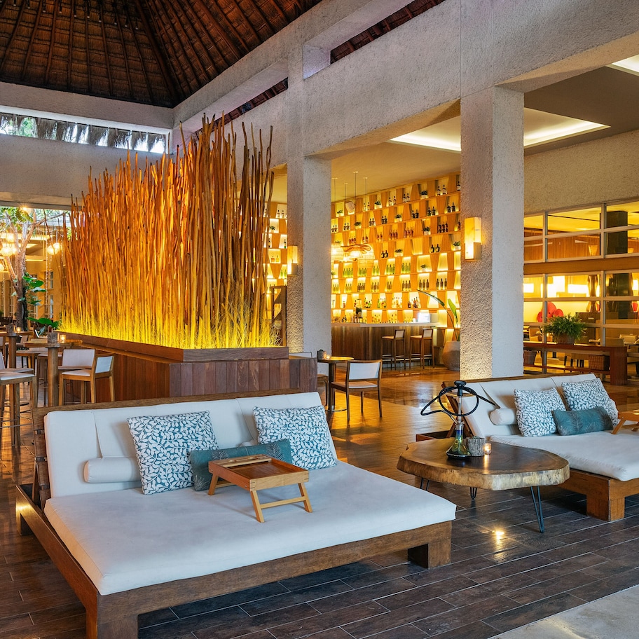 A spacious lobby with a seating area, a decorative wall, and a well-lit bar area.