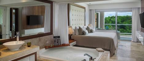 Une chambre d’hôtel moderne dotée d’un grand lit, d’une baignoire, d’une télévision et d’un balcon offrant une vue sur la verdure.