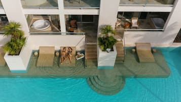 Relax by the pool surrounded by lounge chairs and sunbeds, with hot tubs nearby.