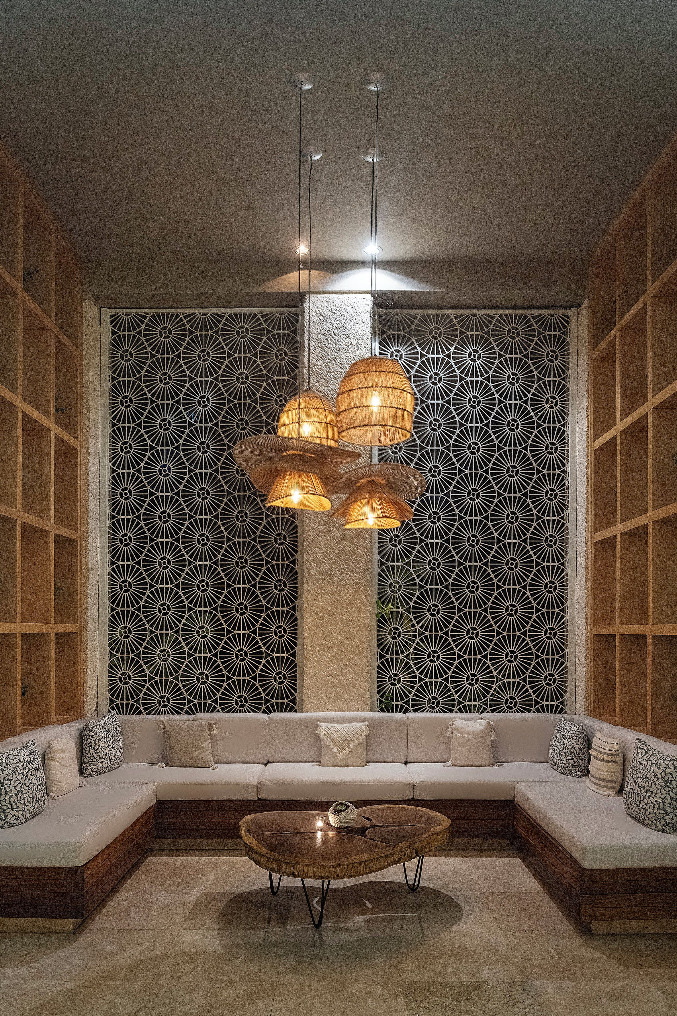 Een moderne woonkamer met een hoekbank, een ronde salontafel en een decoratieve wand met geometrische patronen.