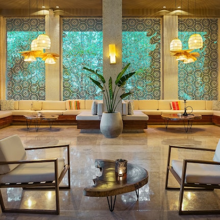 A modern lobby with seating areas, a coffee table, and decorative lighting.