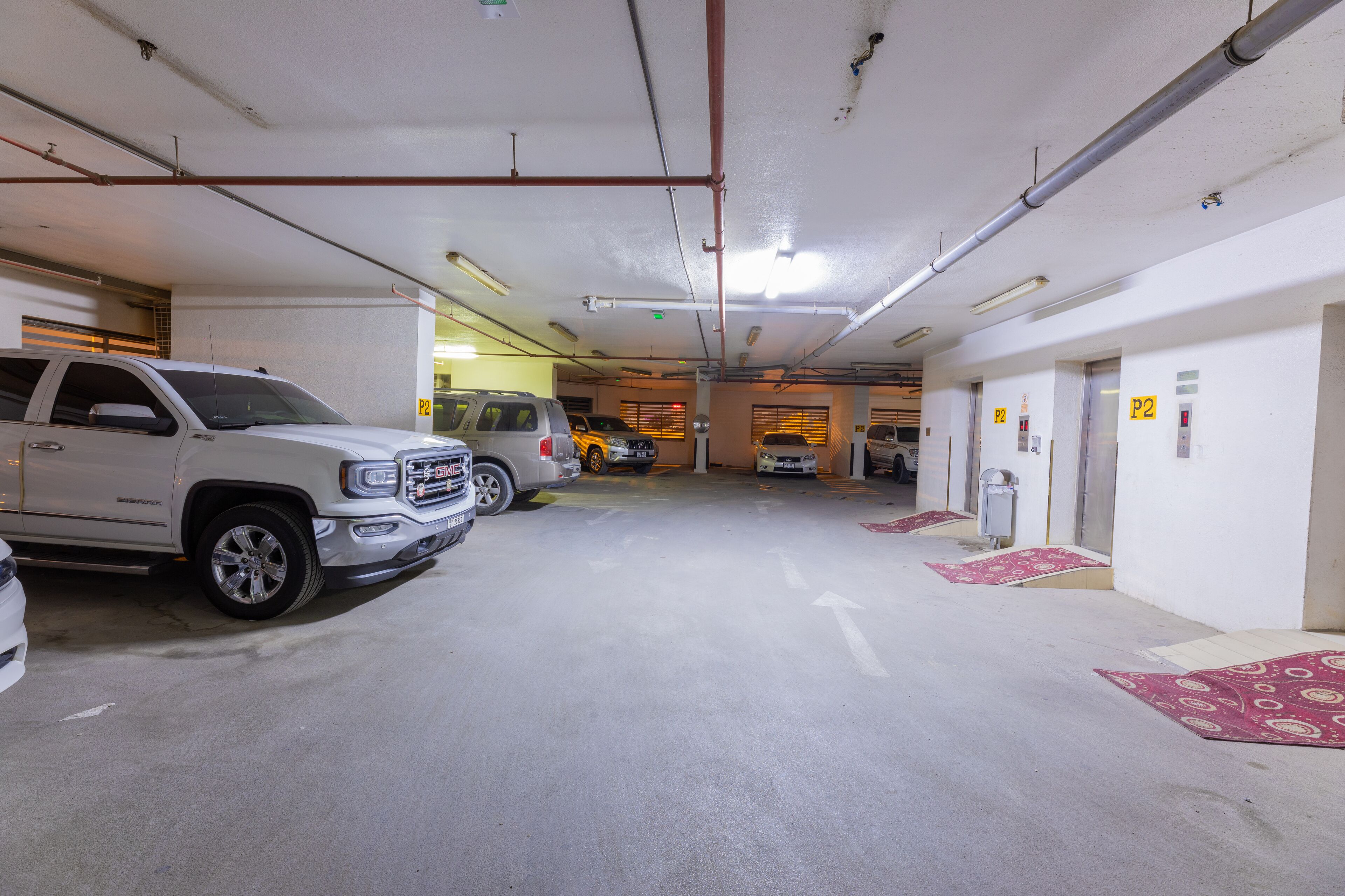 Un parking à plusieurs niveaux, avec des places de stationnement clairement délimitées et des flèches directionnelles peintes sur le sol.
