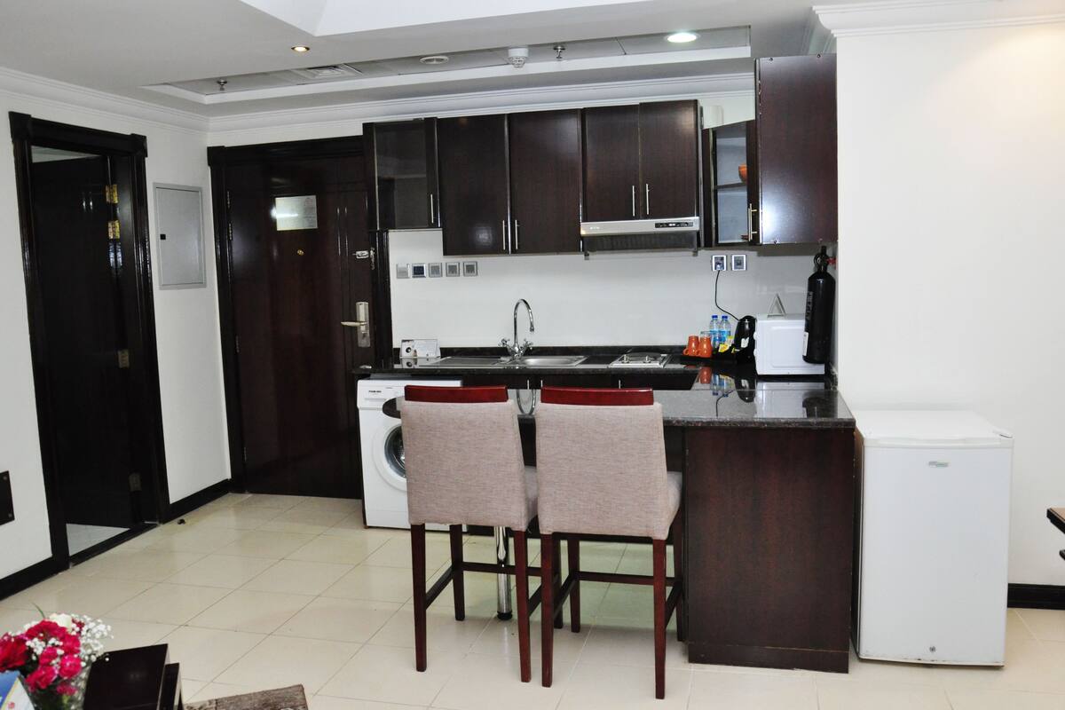 A compact kitchen with dark wooden cabinets, a built-in oven, and a small refrigerator.
