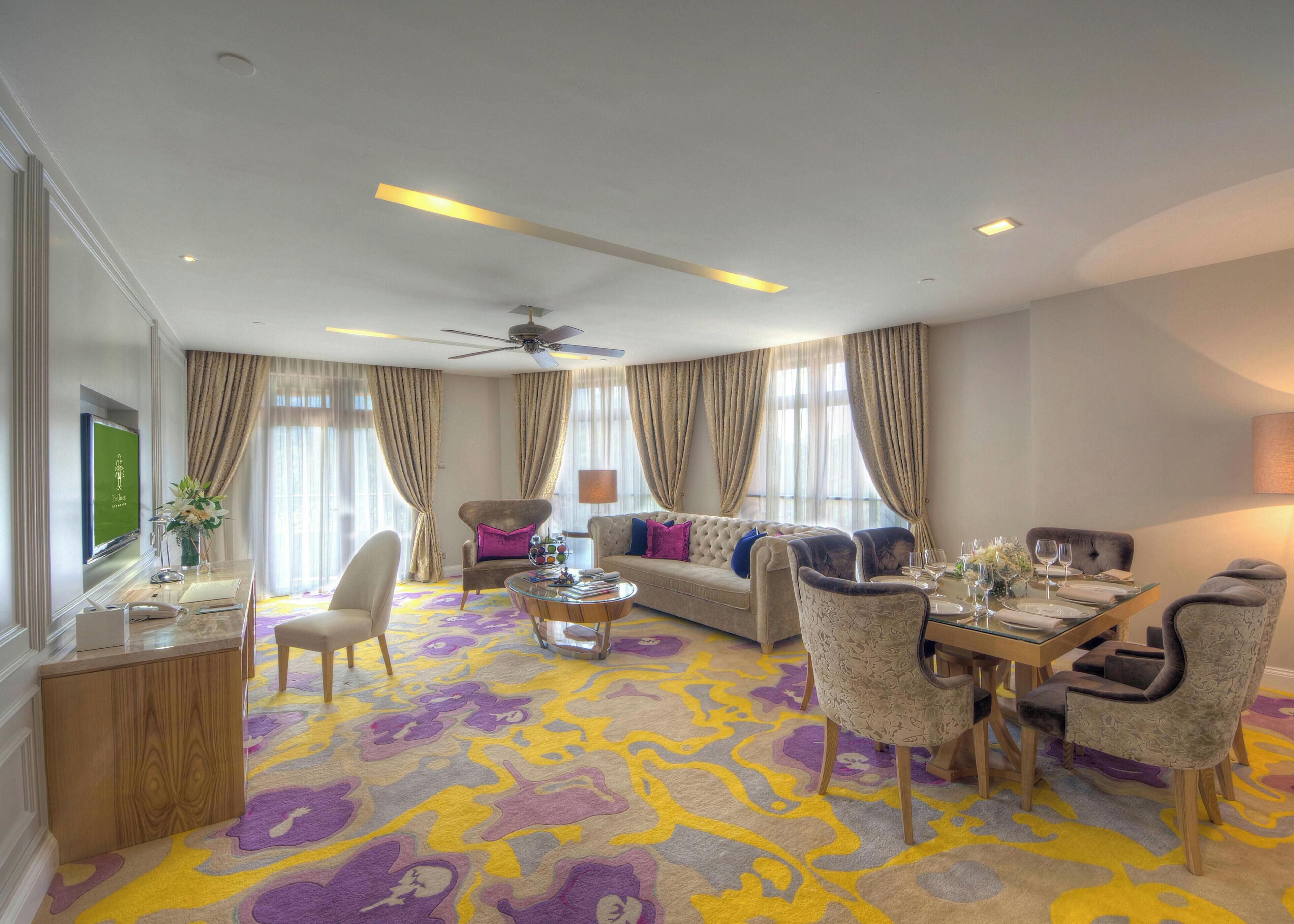 A spacious living room with a sofa, armchairs, a coffee table, and a dining area with a table set for two.
