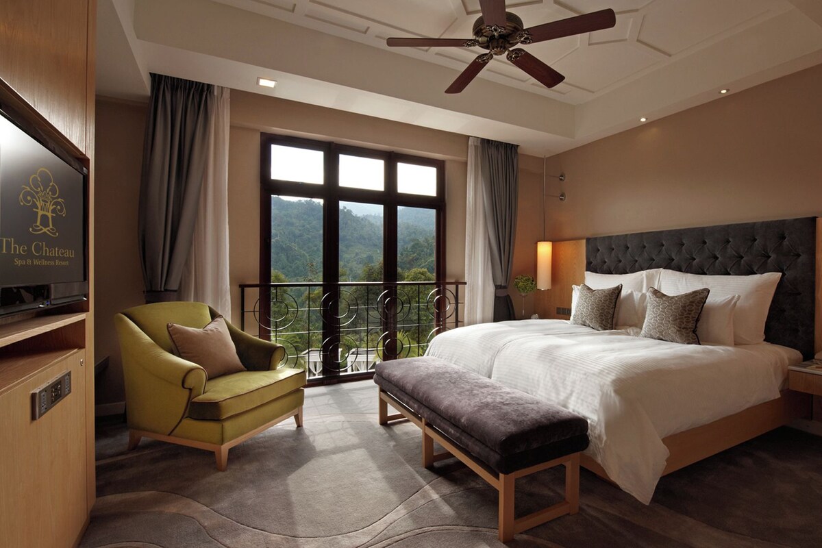 A hotel room with a bed, a sofa, a bench, a TV, and a balcony with a view.