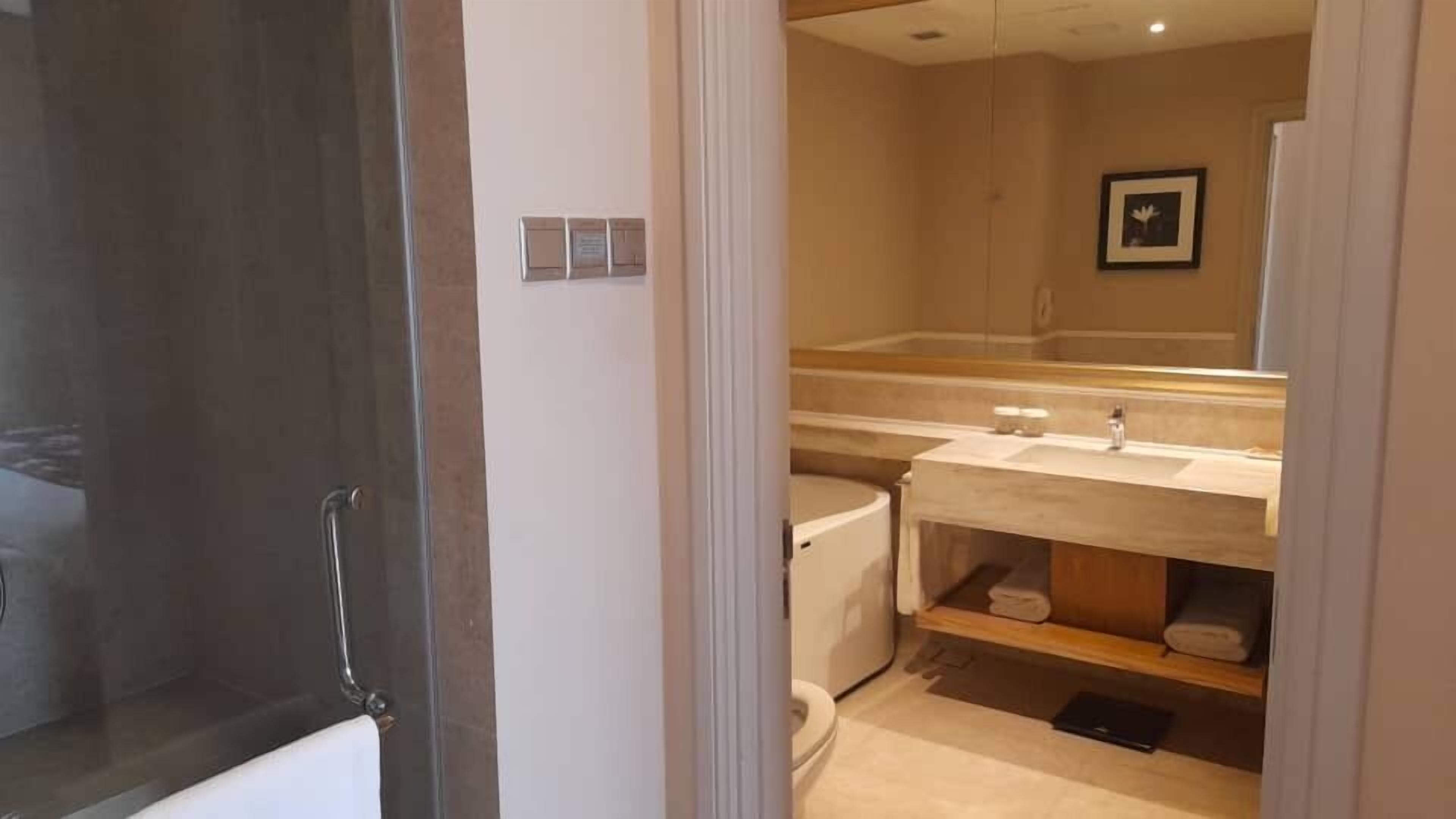 A bathroom with a toilet, sink, and mirror.