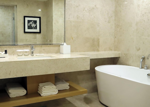 Un baño moderno con un lavabo grande, una bañera y un espejo.