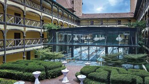 A courtyard with a glass conservatory, a tower, and a yellow building with balconies.