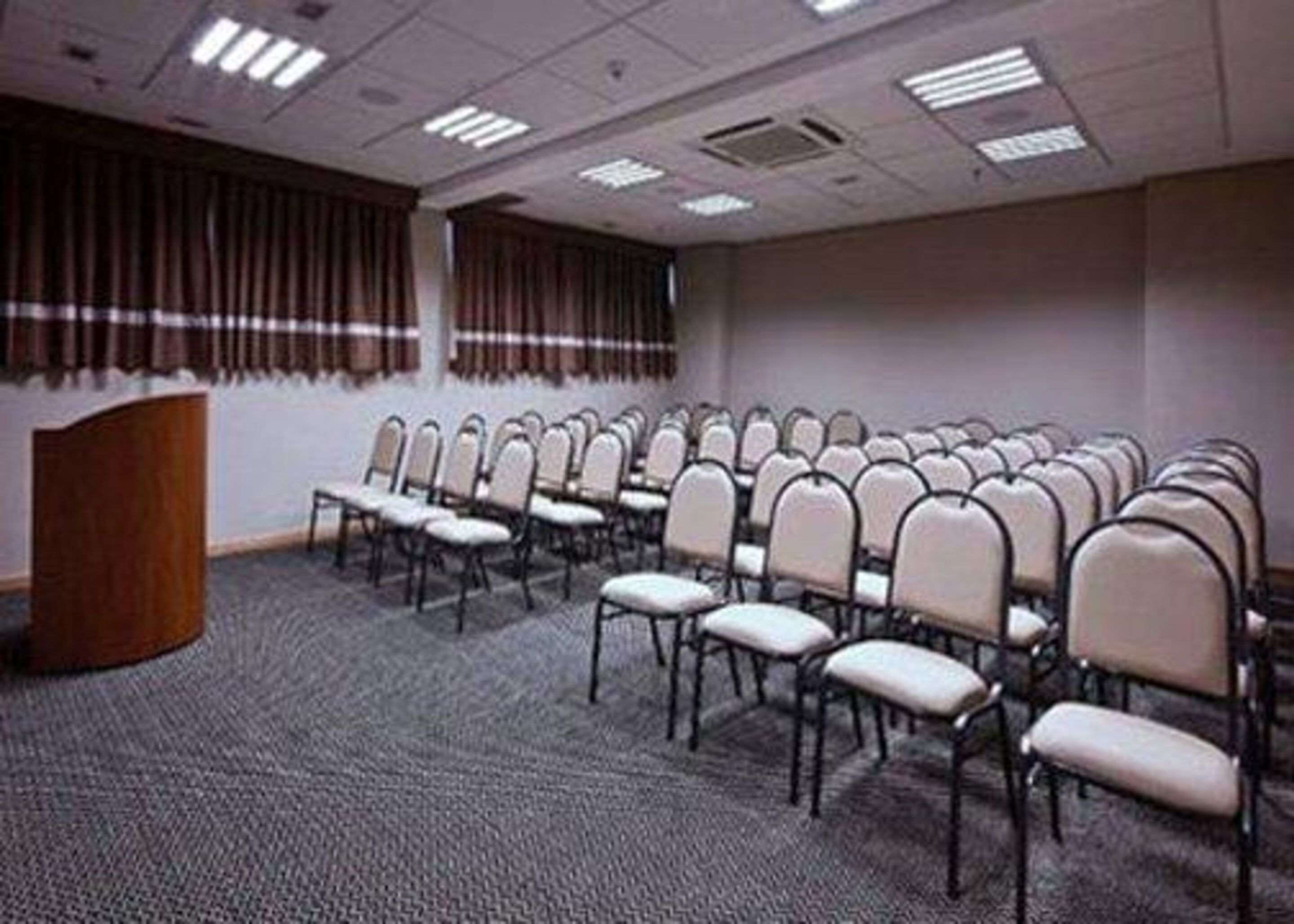 A conference room with rows of chairs, a podium, and a carpeted floor.