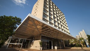 Un hotel moderno con una fachada de vidrio destacada, un acceso cubierto y un cielo despejado.