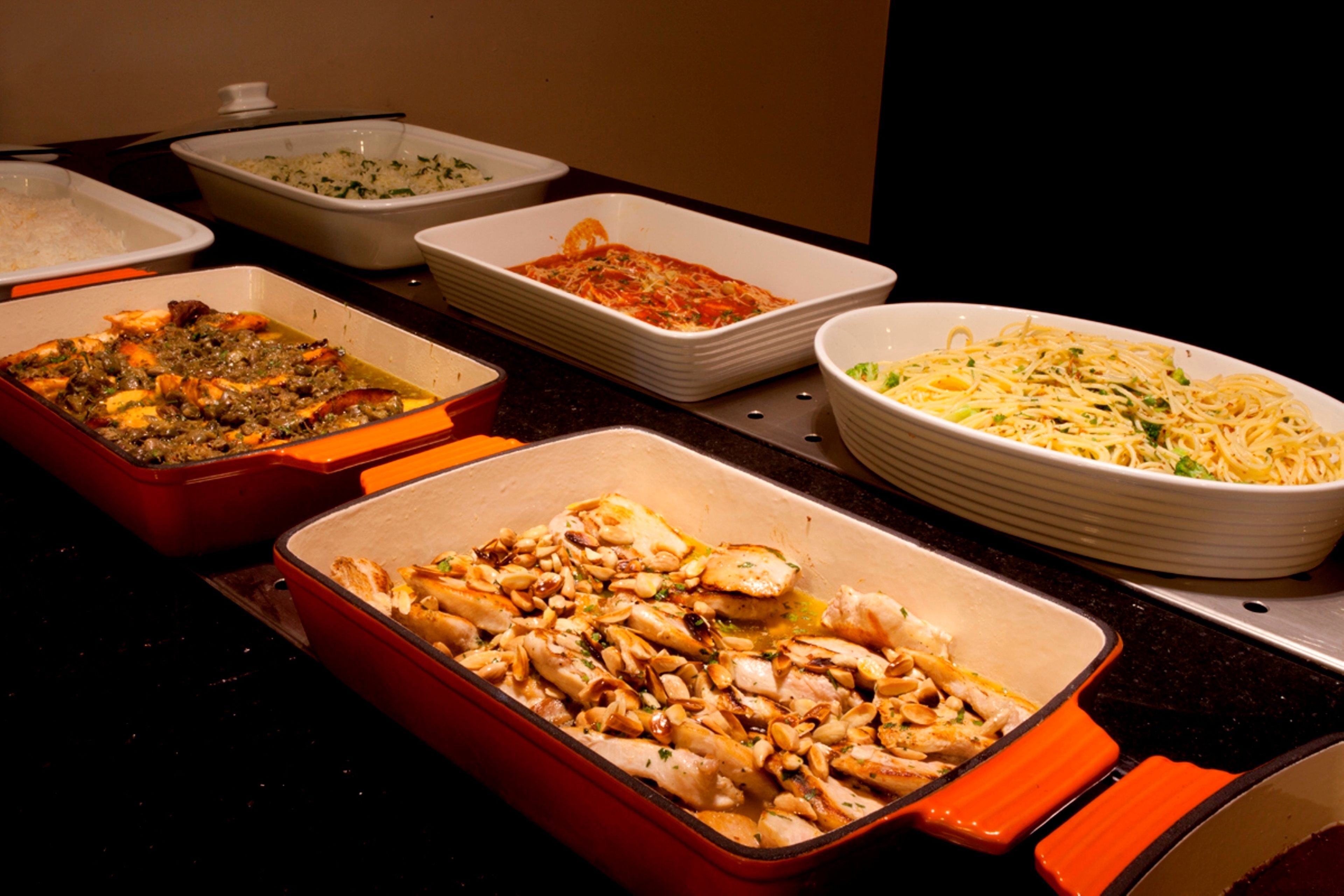 Una mesa de buffet con diversos platos, incluyendo pasta, arroz y cazuelas.
