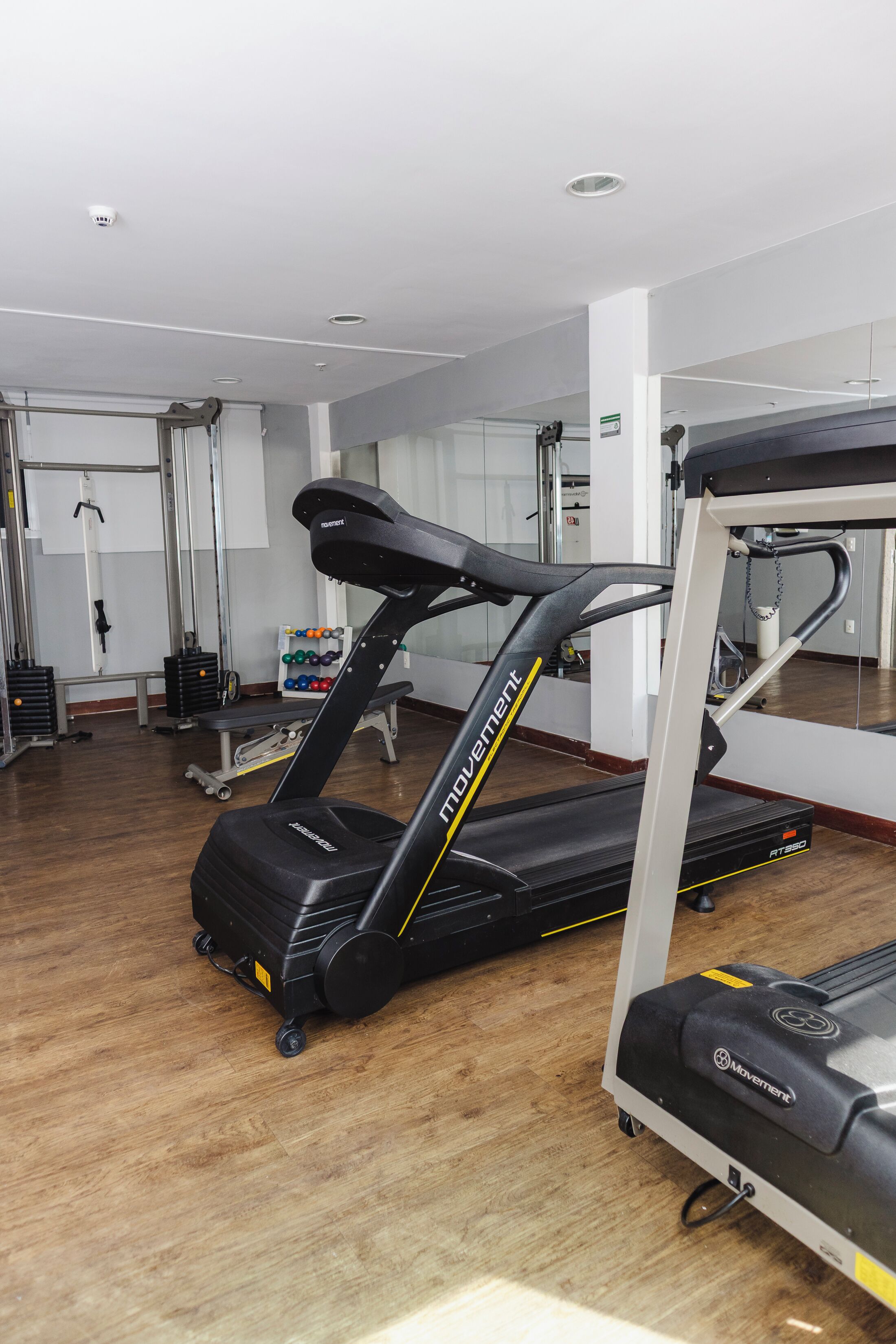 Une salle de sport équipée de tapis de course, d’un rameur et d’un banc de musculation.