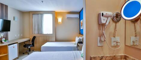Une chambre d’hôtel avec deux lits, un bureau, une télévision, un sèche-cheveux et un miroir.