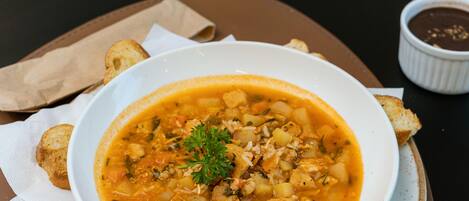 A table with a bowl of soup, bread, and condiments.