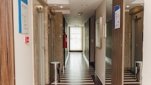 A hotel corridor with a striped floor, wooden paneling, and emergency exit signs. - Comfort Hotel Campos Dos Goytacazes (Campos)