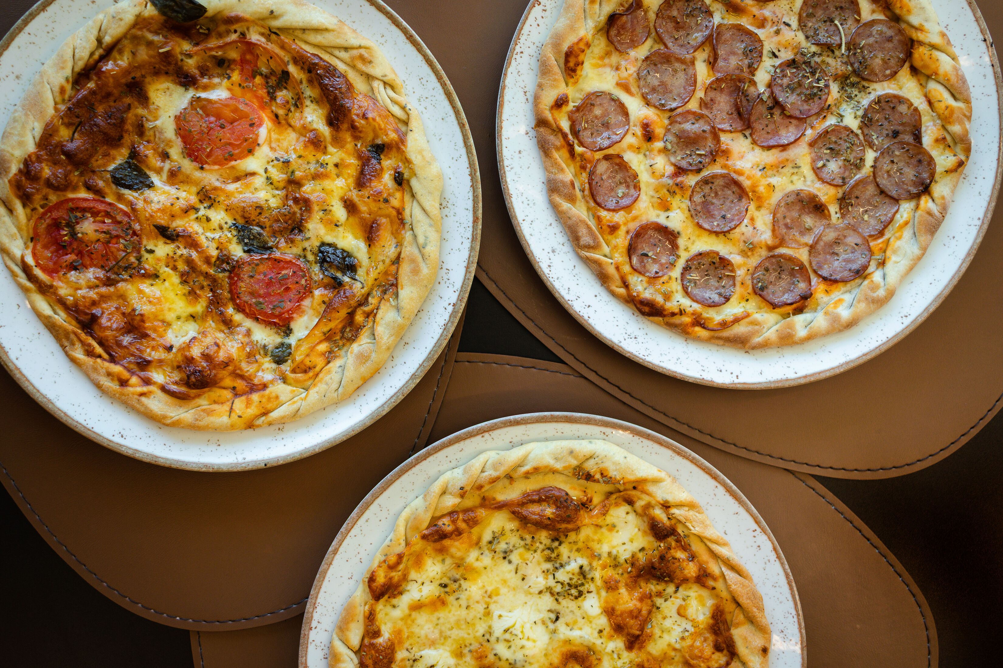 Three pizzas on plates.