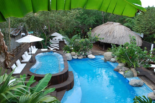 A pool area with a hot tub, lounge chairs, and a thatched-roof structure. - Villas Sur Mer (Negril)