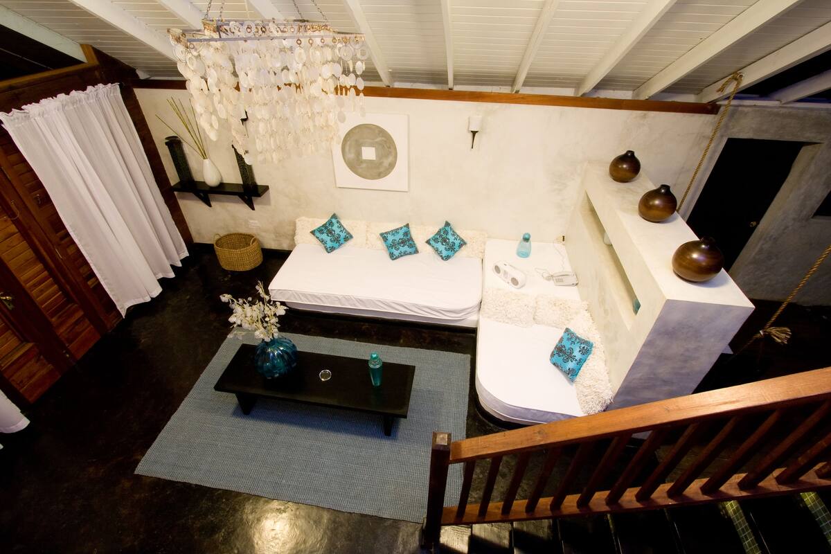 A room with a bed, bedside table, and a hanging light fixture.