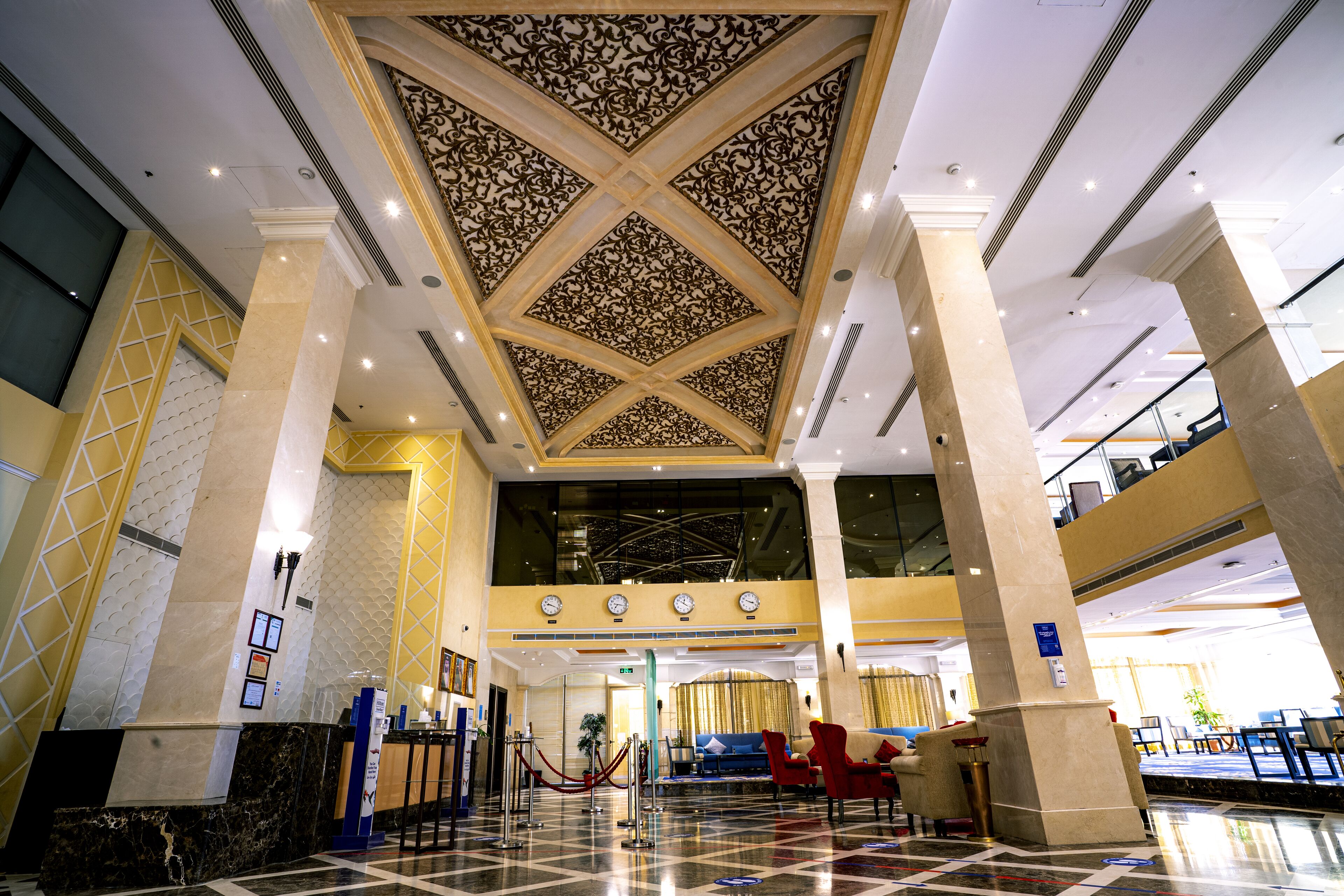 A lobby with a high ceiling, marble columns, and a checkered floor.