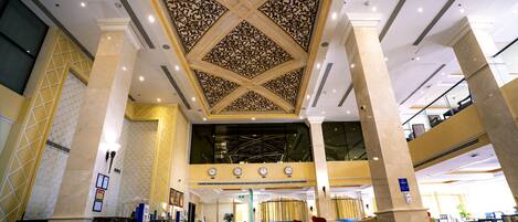 A lobby with a high ceiling, marble columns, and a checkered floor.