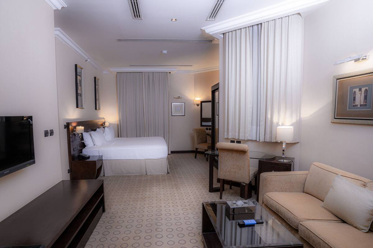 Una habitación de hotel con cama, sofá, televisión, escritorio y una silla.