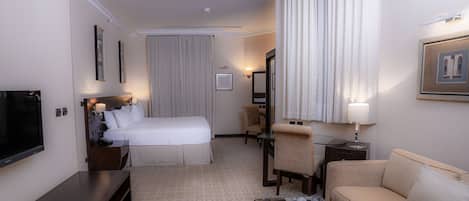 Una habitación de hotel con cama, sofá, televisión, escritorio y una silla.