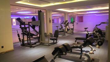 Un gimnasio moderno con diverso equipo de ejercicio, incluyendo cintas de correr y máquinas de pesas, y un diseño espacioso.