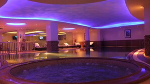 A spa area with a hot tub, seating, and a pool. - DoubleTree by Hilton Hotel Dhahran (Al Khobar)