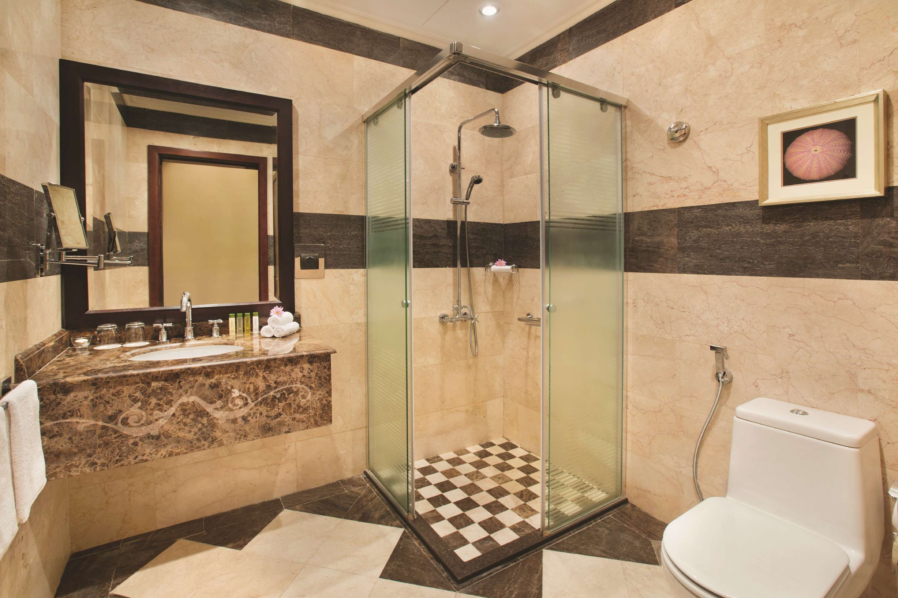 A modern bathroom with a glass-enclosed shower, a marble vanity, and a toilet.