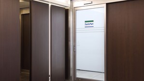 Ein moderner Aufzug mit einem FamilyMart-Schild, das einen Einzelhandelsladen im Erdgeschoss kennzeichnet.
