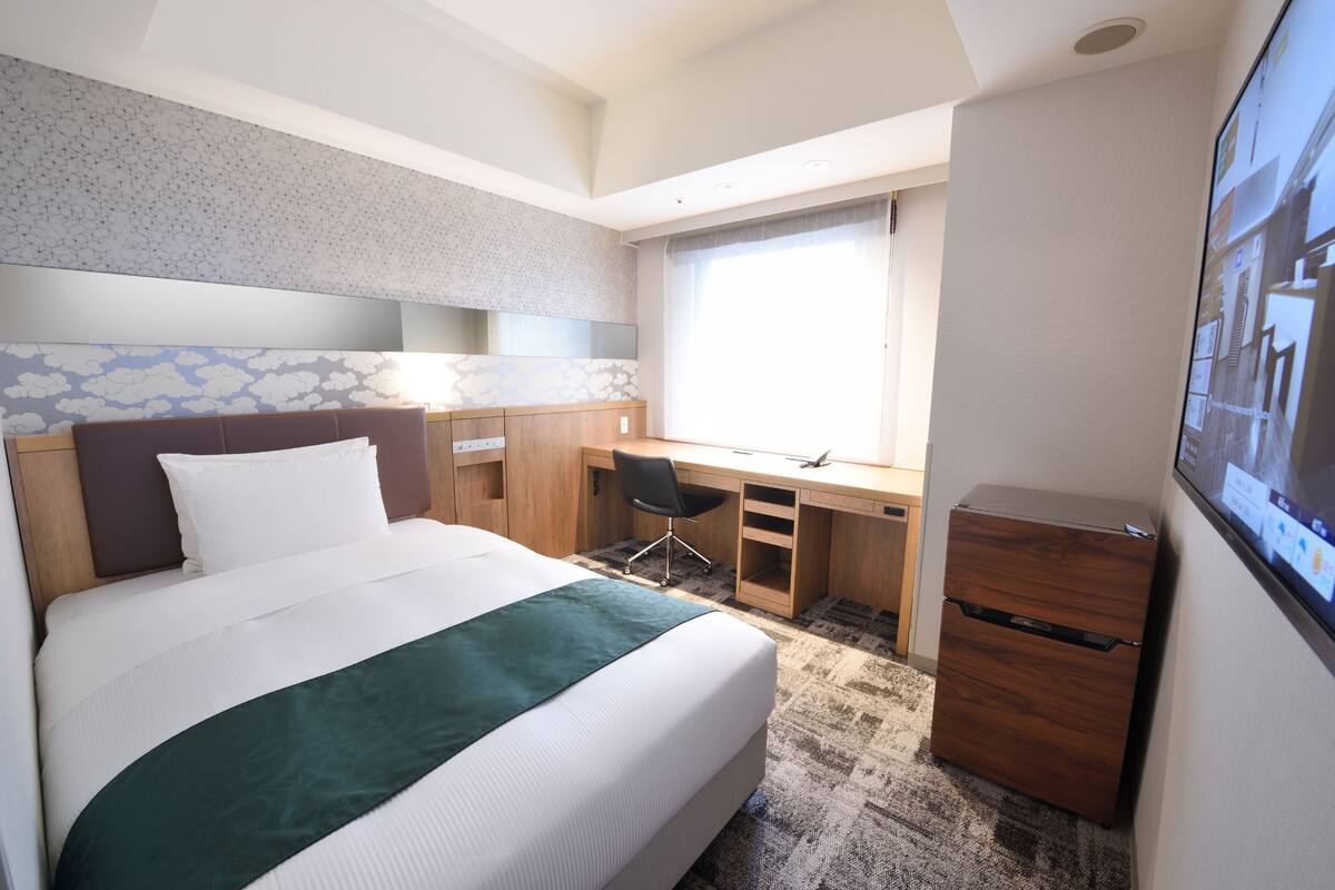 Ein Hotelzimmer mit einem großen Bett, einem Schreibtisch, einem Stuhl und einem Kleiderschrank.